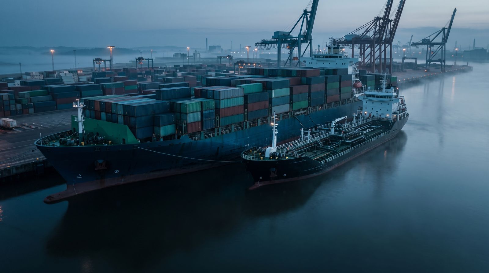 Container ship and tanker in port at dusk